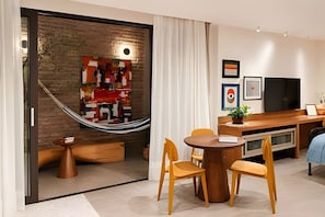 A modern living room with a dining area, a hammock, and a TV. - Living Studios (Rio de Janeiro)