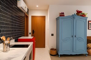 A room with a white marble countertop, a red chair, a blue wardrobe, and a wooden door. - Living Studios (Rio de Janeiro)