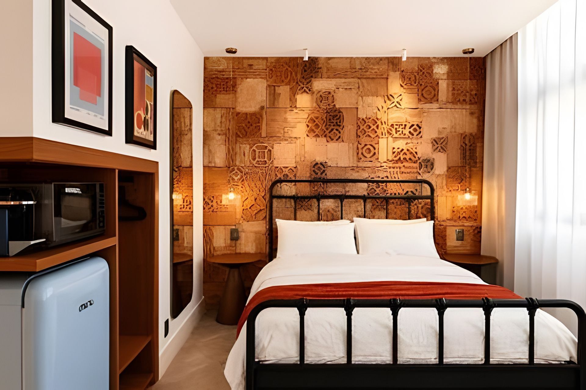 Una habitación de hotel con una cama, un microondas y una pared con intrincados grabados.