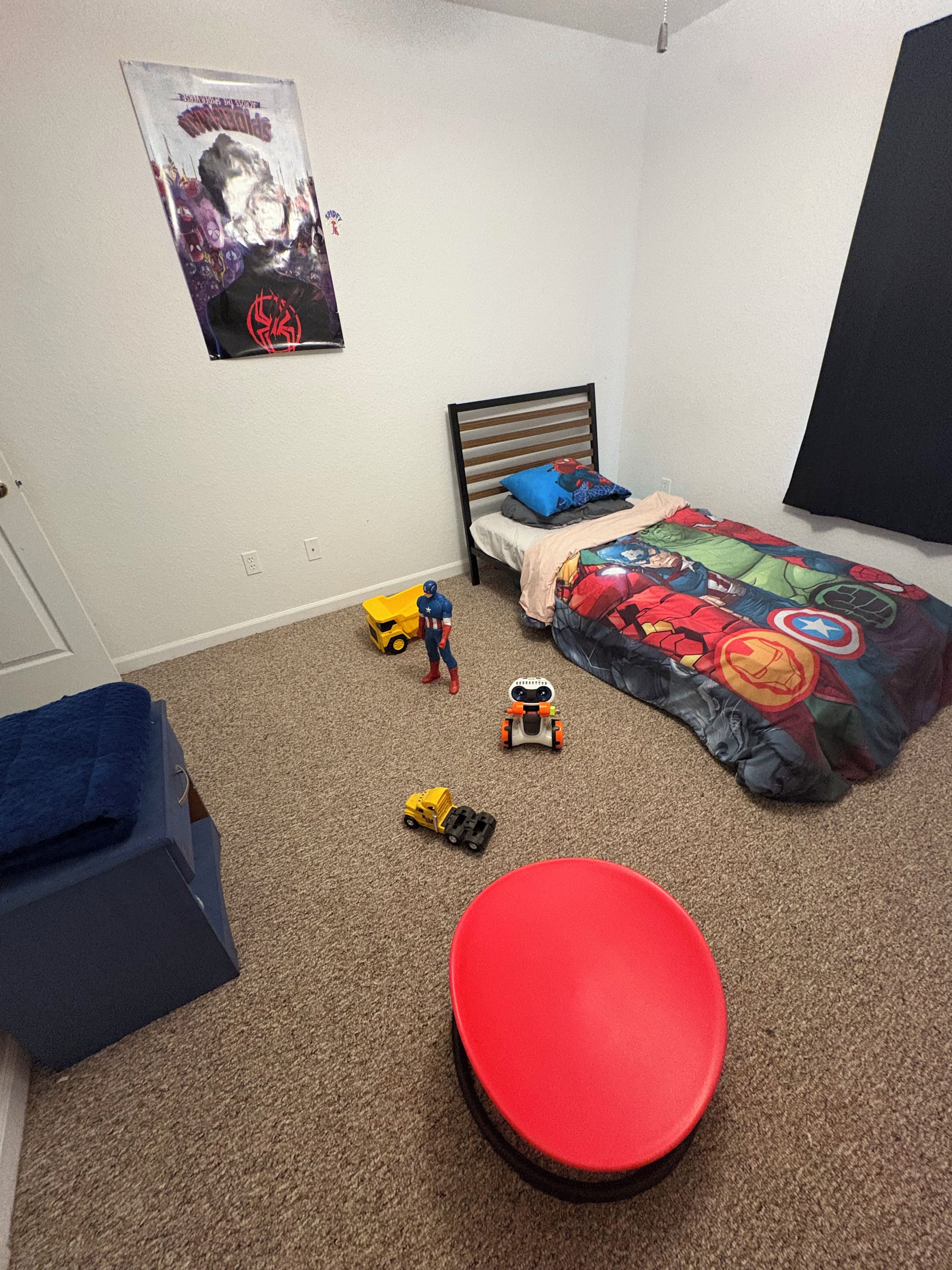 Un dormitorio con cama, un cartel en la pared y juguetes en el suelo.