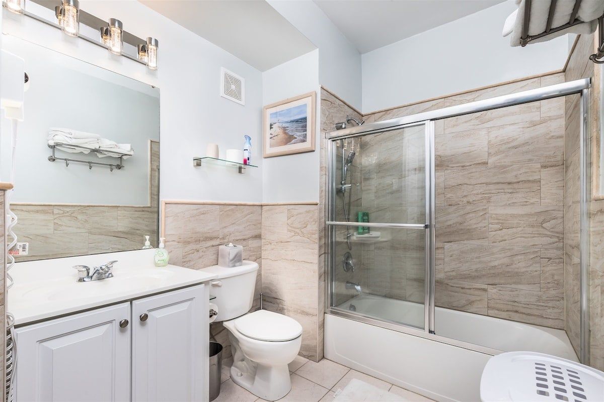 A bathroom with a glass-enclosed shower, a white sink, and a toilet.