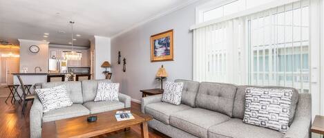 A living room with a sofa set, a coffee table, and a dining area in the background.