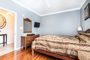 Ein Schlafzimmer mit einem hölzernen Bett, einem Schminktisch, einem Spiegel, einem Fernseher und einer Lampe.