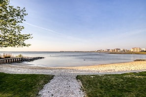 A coastal walkway leading to a beach with a clear view of the ocean and distant buildings. - Sunset Island 37 Fountain Drive West, Unit 3E (Ocean City)