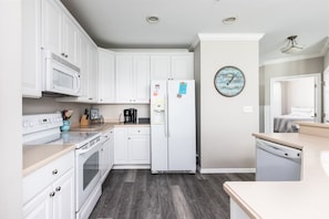 A modern kitchen with white cabinets, a built-in microwave, an oven, a refrigerator, and a dishwasher. - Sunset Island 37 Fountain Drive West, Unit 3E (Ocean City)
