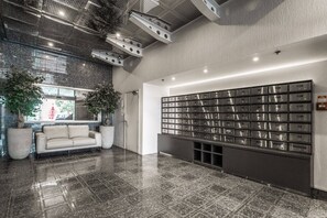 A lobby with a sofa, a large mail slot wall, and a tiled floor. - Large Waterfront Stay by Britomart & Harbour (Auckland)