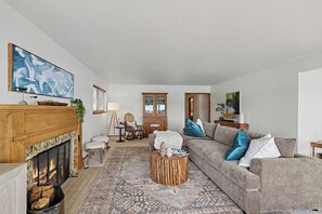 A living room with a fireplace, a sofa, a coffee table, and a painting on the wall.
