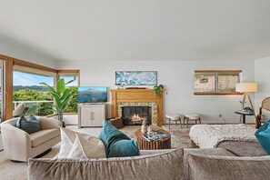 A living room with a fireplace, a television, and a view of the outdoors.