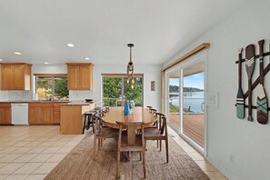 A modern kitchen with wooden cabinets, a central island, and a dining area with a round table and chairs.