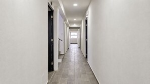 A corridor with white walls, a tiled floor, and doors on both sides.
