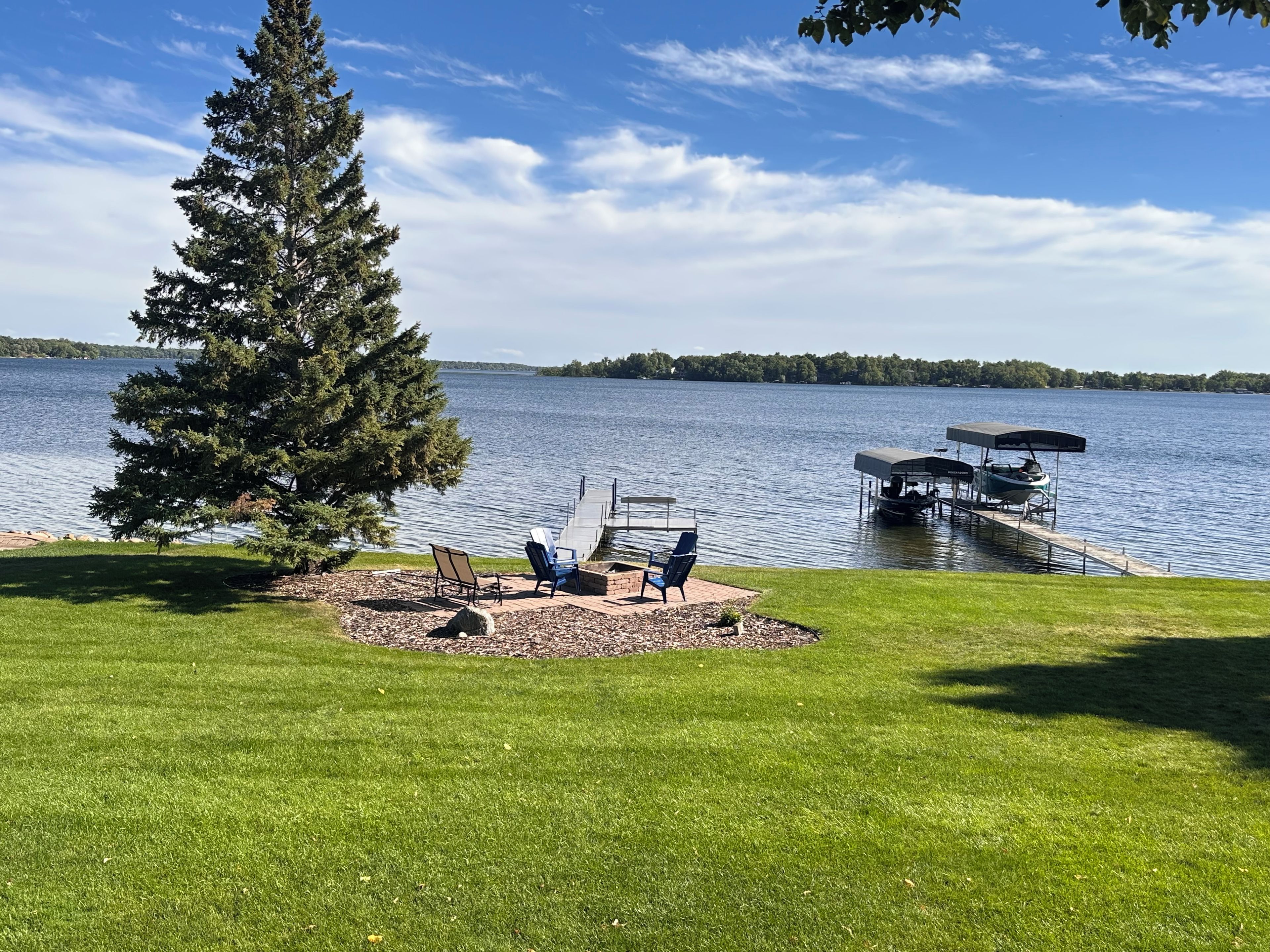 Une terrasse au bord du lac, avec des sièges extérieurs et une jetée qui s’avance dans l’eau.