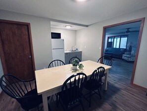 A dining area with a table and chairs, a kitchen in the background, and a view into a living room with a sofa and a patterned chair. - Stupendous Lake Ida Home on the Water and close to Carlos Creek Winery. Lic2061 (Alexandria)