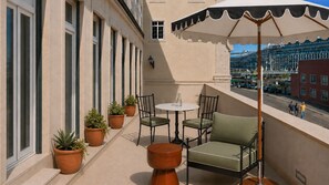 A balcony with a table and chairs, potted plants, and a view of the cityscape. - Ando Living - Tejo Palace - 101 (Lisboa)