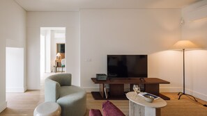Ett modernt vardagsrum med en platt-TV, ett soffbord i trä, en soffa och en golvlampa.