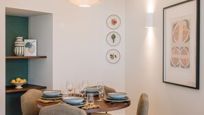 A dining area with a round table set for four, surrounded by wicker chairs. - Ando Living - Tejo Palace - 102 (Lisboa)