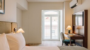 A hotel room with a bed, two bedside lamps, a desk with a chair, a television, and a balcony door. - Ando Living - Tejo Palace - 102 (Lisboa)