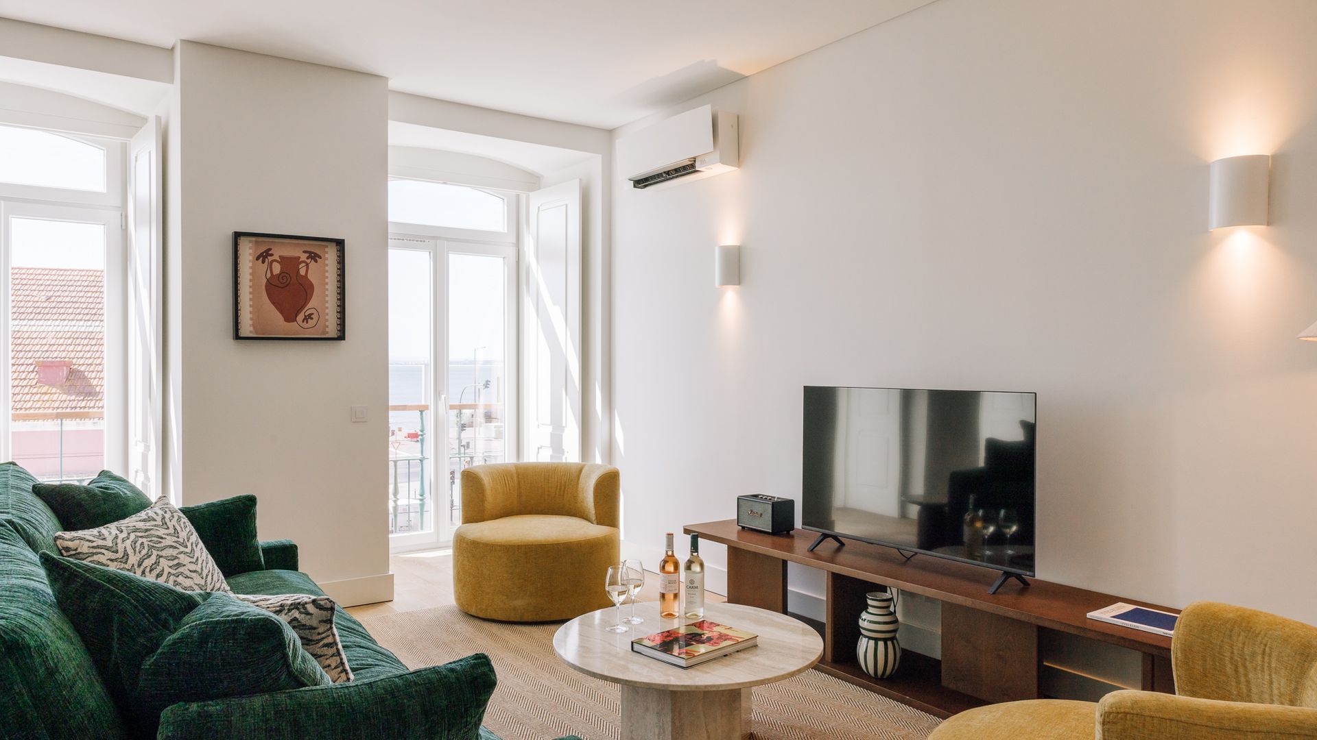 Un salon moderne avec un canapé, un fauteuil et une table basse sur laquelle se trouvent un livre et des lunettes.