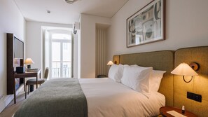 A hotel room with a bed, bedside lamps, a desk with a lamp, a chair, and a large window. - Ando Living - Tejo Palace - 202 (Lisboa)