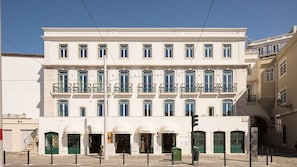 A multi-story building with a row of shops on the ground floor, each with a distinct name. - Ando Living - Tejo Palace - 203 (Lisboa)