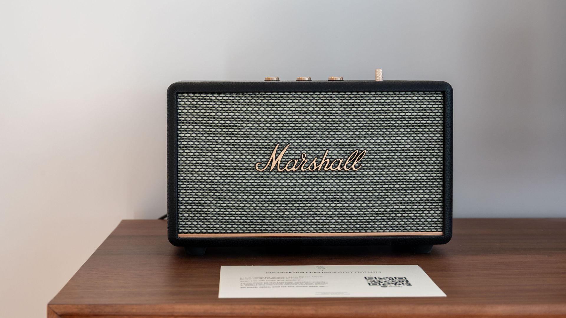 Un amplificador Marshall sobre una mesa de madera con un código QR y una etiqueta blanca.