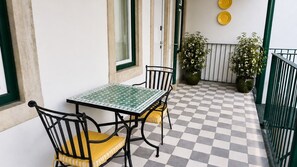 A checkered outdoor patio with a table and chairs, potted plants, and a railing. - Ando Living - Tejo Palace - 204 (Lisboa)
