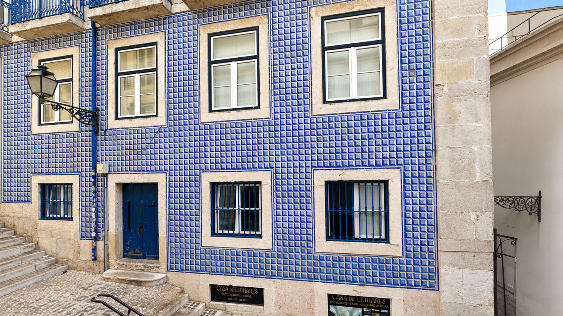 A building with blue tiled facade, multiple windows, and a blue door.