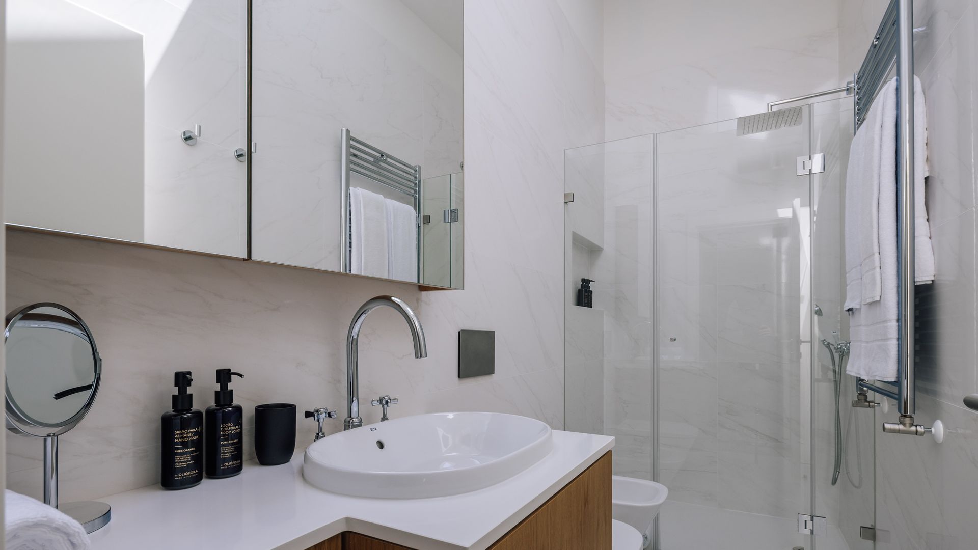 A modern bathroom with a white sink, a mirror, and a glass shower enclosure.