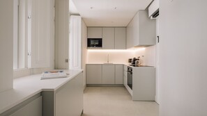 Eine moderne Küche mit weißen Schränken, einer eingebauten Mikrowelle und einer Arbeitsplatte mit Kaffeemaschine.