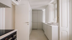 A narrow hallway with a kitchen area, a door with a handle, and a window. - Ando Living - Tejo Palace - 301 (Lisboa)