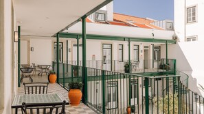 Ein Balkon mit Sitzgelegenheiten im Freien, einem Schachbrettfußboden und einem Gebäude mit einem Ziegeldach.