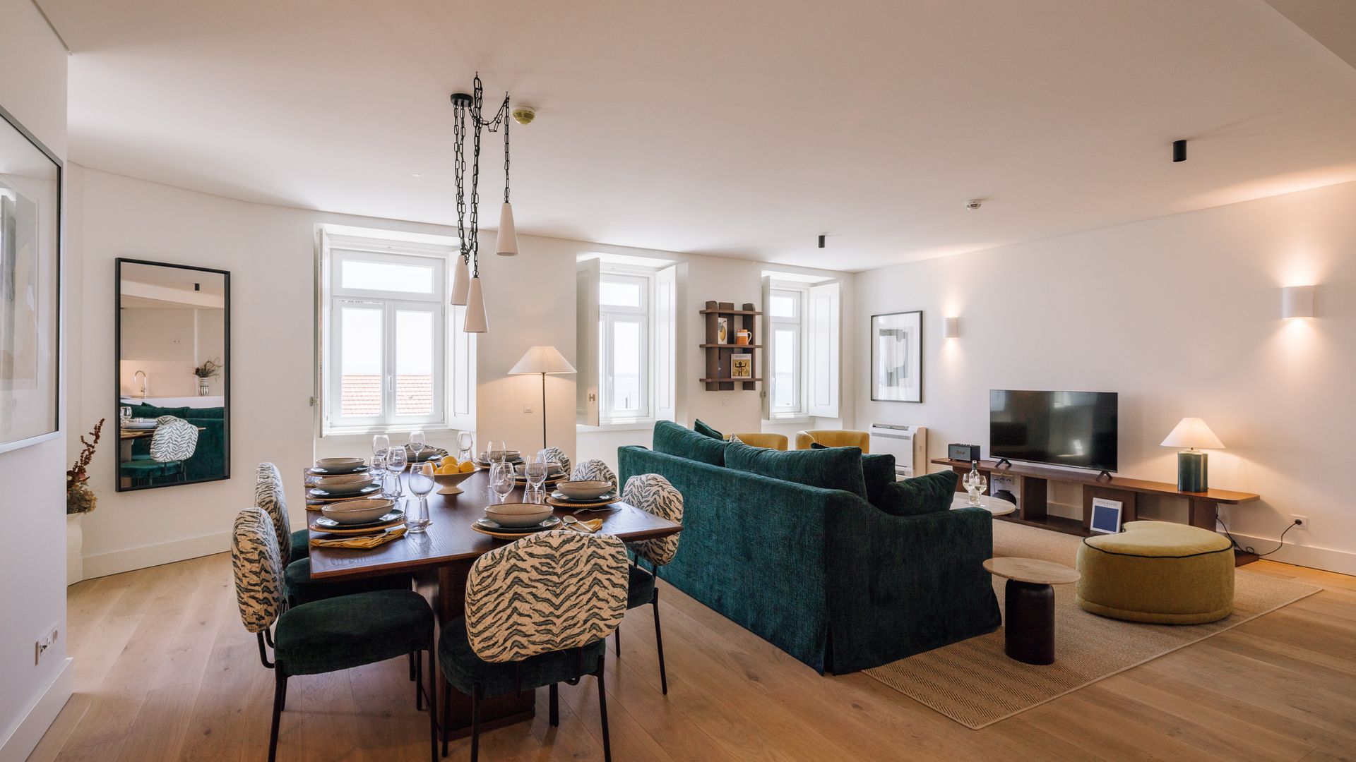 A modern living room with a dining area, a sofa set, a television, and a fireplace.
