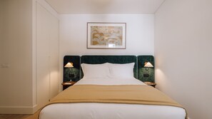 Ett hotellrum med en säng, två sänglampor, ett inramat konstverk på väggen och en dörr till vänster.