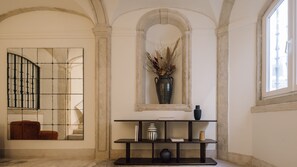 A room with a large mirror, a console table with decorative items, and a window with a view. - Ando Living - Tejo Palace - 303 (Lisboa)
