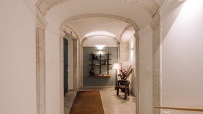 A hallway with an arched ceiling, a wooden bench, a lamp, and a shelf with decorative items. - Ando Living - Tejo Palace - 303 (Lisboa)