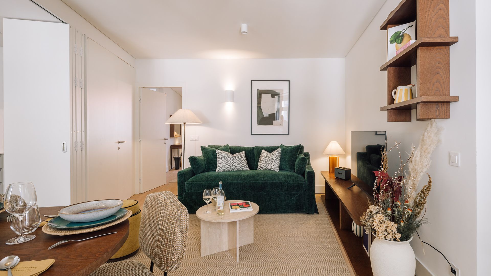 A modern living room with a green sofa, a round coffee table, and a bookshelf.