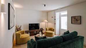 A modern living room with a sofa, two armchairs, a coffee table, a flat-screen TV, and a lamp. - Ando Living - Tejo Palace - 304 (Lisboa)