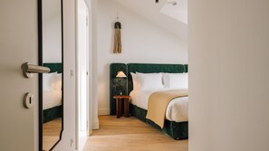 A hotel room with a mirrored door, a bed with a green headboard, a bedside table with a lamp, and a hanging light fixture. - Ando Living - Tejo Palace - 400 (Lisboa)