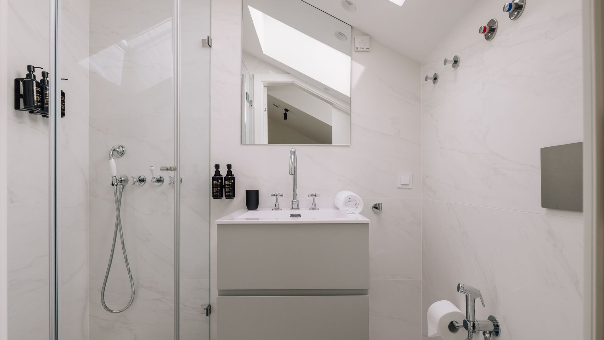 Un baño moderno con ducha envuelta en vidrio, un lavabo con espejo y un inodoro.