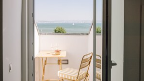A balcony with a table and chairs, a bowl, and two wine glasses. - Ando Living - Tejo Palace - 401 (Lisboa)