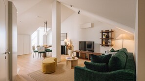 Uma sala de estar moderna com um sofá verde, televisão e área de jantar com mesa e cadeiras.