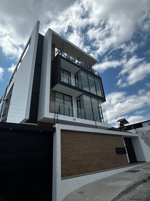 A modern two-story building with a flat roof, large windows, and a wooden facade. - Modern STUDIO in a central, tourist-friendly area of the city (Manta)