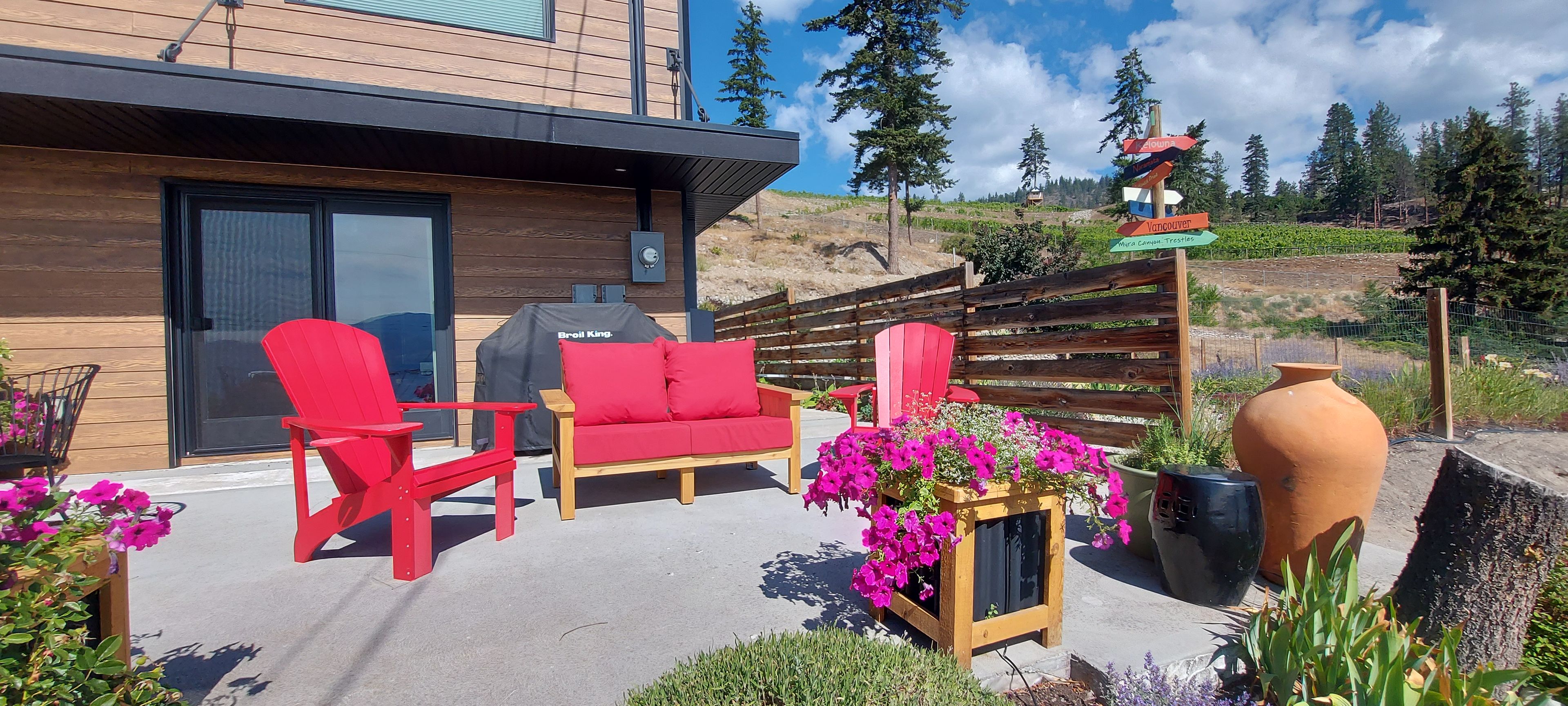 Une terrasse avec des chaises rouges, une table en bois et un barbecue.