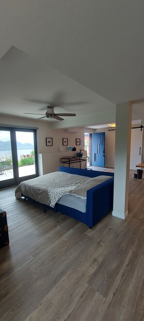 Een slaapkamer met een bed, een plafondventilator, een bureau en uitzicht op de omgeving.