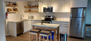 Een moderne keuken met roestvrijstalen apparatuur, houten barstoelen en inbouwplanken.