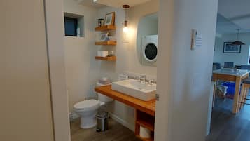Une salle de bain moderne équipée de toilettes, d’un lavabo et d’un lave-linge.