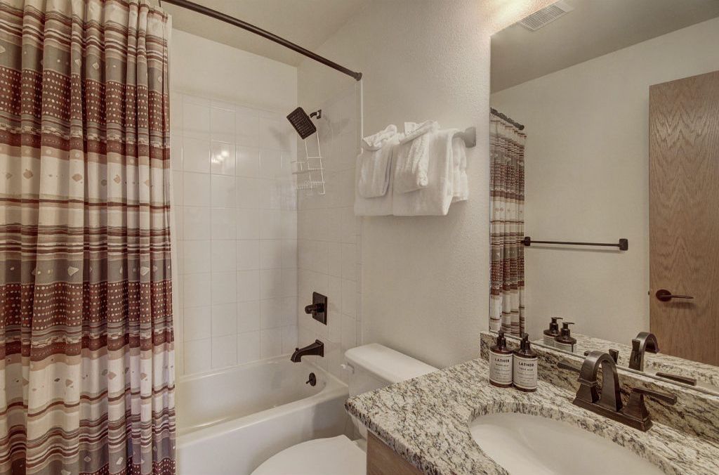 A bathroom with a shower, toilet, and sink.
