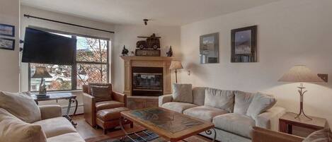 A living room with a fireplace, leather sofas, a coffee table, and a television.