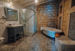 Un baño con ducha de vidrio, bañera independiente y suelo estampado.