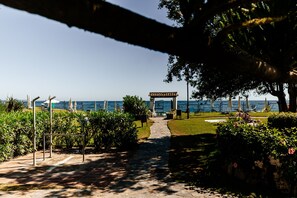A pathway leading to a building with a view of the sea. - 03 Beach Home by Abarzo (Marbella)