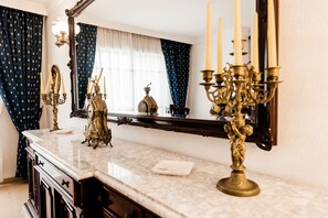 A bathroom with a marble countertop, a mirror, a vanity with a sink, and a decorative candelabra. - 03 Beach Home by Abarzo (Marbella)